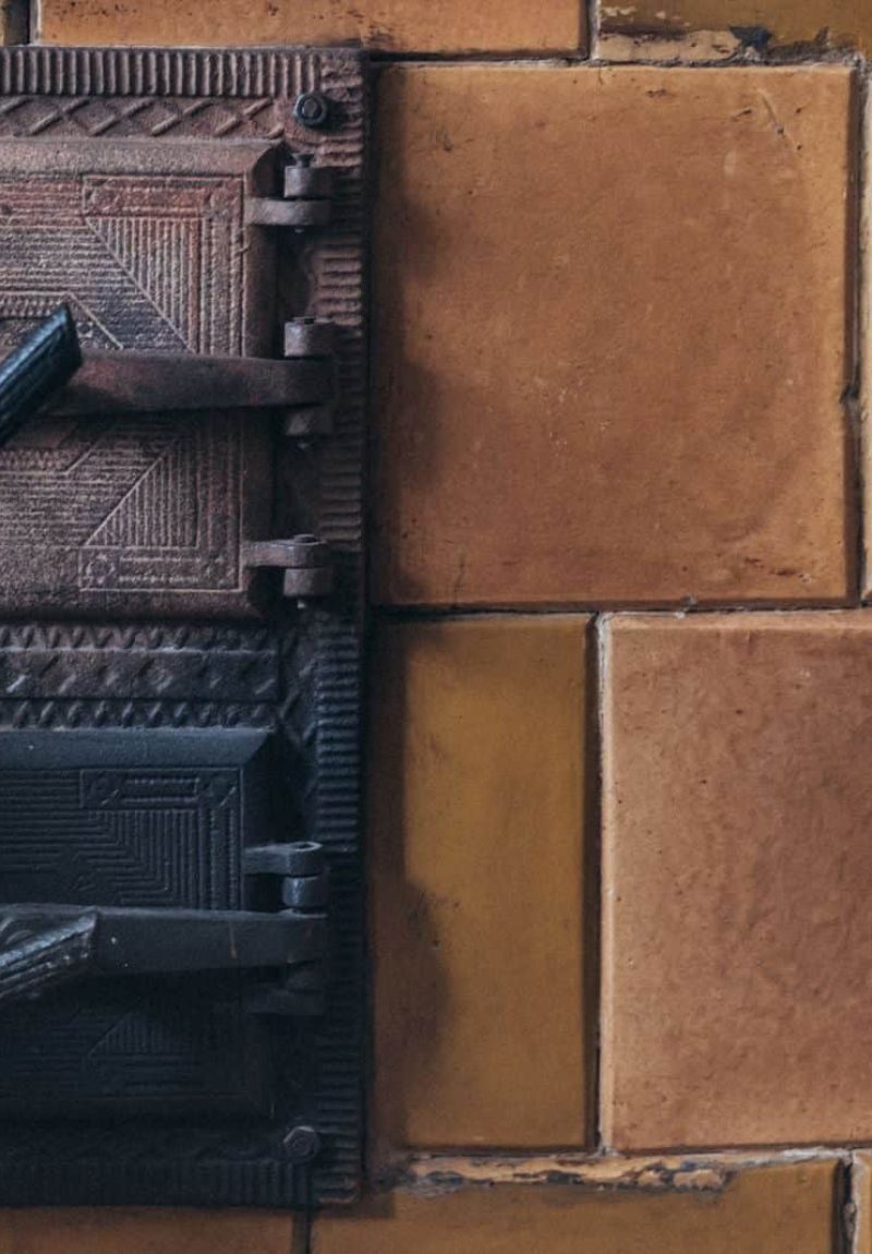 Close-up of a vintage iron latch on a rustic tan brick wall, showcasing aged texture and detail.